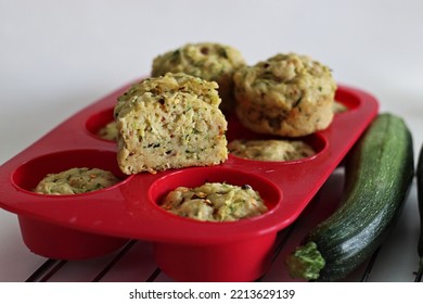 Cheese Zucchini Breakfast Muffins. Savory Breakfast Muffins Made Of Whole Wheat Flour, Shredded Zucchini, Grated Cheese And Herbs. Shot On White Background With Muffins Inside The Red Silicon Mould.