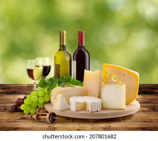 Cheeseboard, Grape And Wine On Wooden Table In Countryside