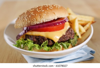 cheeseburger with french fries on a white plate. Shallow depth of field.