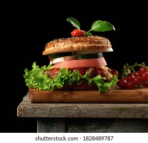 Cheeseburger With Minced Meat, Green Lettuce And Ketchup On A Wooden Brown Kitchen Board, Chili Pepper On Top