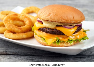 Cheeseburger served with deep fry onion rings on the white square dish and wooden board background - Powered by Shutterstock