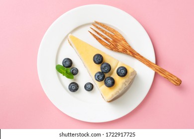 Cheesecake slice with blueberries on pink background, table top view