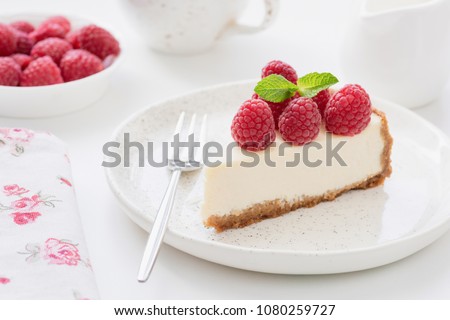 Cheesecake slice with raspberries on white plate. Slice of plain cheesecake. Raspberry cheesecake. Tasty cheesecake