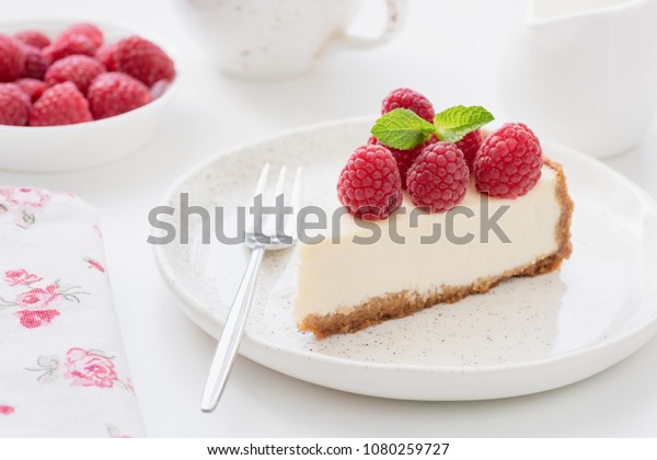 Cheesecake slice\
with raspberries on white plate. Slice of plain cheesecake.\
Raspberry cheesecake. Tasty\
cheesecake