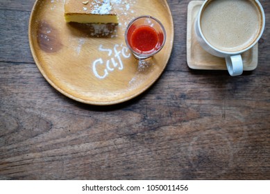 cheesecake with strawberry sauce topping & icing sugar. hot cappuccino coffee in white cup on wood table in cafe - top view - Shutterstock ID 1050011456