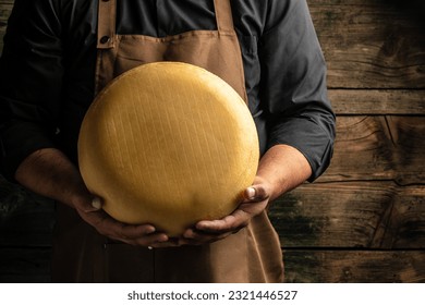 cheesemaker hold big slice of cheese maasdam in hand. Cheese with big holes. head of handcrafted hard cheese. Long banner format. top view. - Powered by Shutterstock