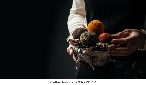 cheesemaker Woman hands hold basket Belper Knolle cheese in the form of small balls on a dark background,