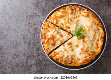 Cheesy Baked Spaghetti Pie with Ground beef, spicy and tomato sauce closeup in the plate on the table. Horizontal top view from above