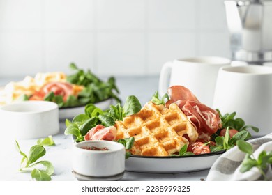 Cheesy belgian waffles served with ham, tomatoes and lettuce corn on white marble background . Savory waffles. Healthy breakfast. Text space. Horisontal