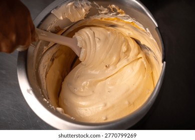 Chef adding fresh tumbo fruit marmalade into a creamy base to create artisanal gourmet ice cream in a stainless steel bowl