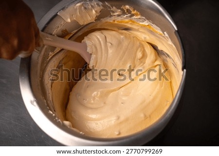 Chef adding fresh tumbo fruit marmalade into a creamy base to create artisanal gourmet ice cream in a stainless steel bowl
