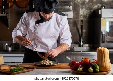 Chef añadiendo piquismo al plato, terminando con sabor a la comida en el plato, usando gorra y delantal, cocinar solo en la cocina del restaurante