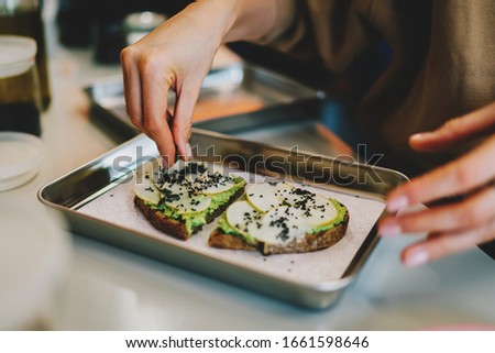 Chef adding pumpkin seeds to delicious vegetarian sandwiches for the breakfast. Healthy and tasty gluten free food. Cooking using natural ingredients.Simple food cooking using avocado and rye bread