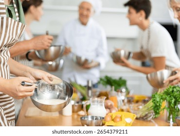 Chef apprentices learn how to properly beat eggs with a whisk in a cooking class
