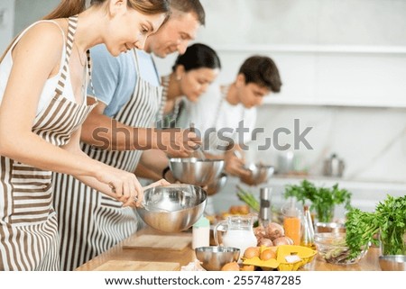 Chef apprentices learn how to properly beat eggs with a whisk in a cooking class