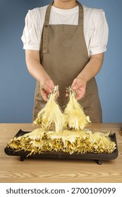 Chef in apron presenting dried corn husks on wooden cutting board for traditional cooking and food preparation in professional kitchen setting
