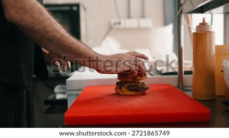Chef assembling a classic smash burger, adding top bun for fast food service