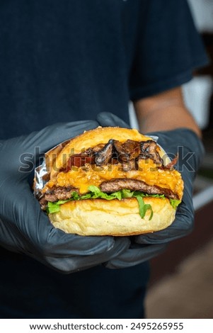 A chef is assembling or stacking a cheeseburger with mushroom topping