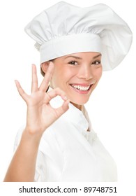 Chef Baker Or Cook Showing Ok Hand Sign For Perfection. Woman Chef Smiling Happy And Proud. Portrait Cook Wearing Chefs Hat Isolated On White Background. Mixed Race Asian Caucasian Female Model.