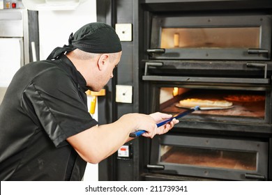 Chef Baker In Uniform Making Pizza At Restaurant Kitchen Stove