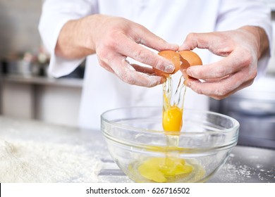 Chef breaking raw egg into bowl while preparing dough - Powered by Shutterstock