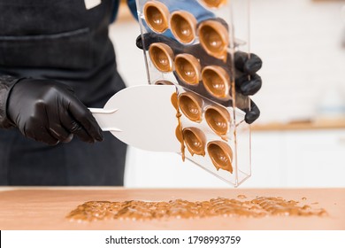 Chef or chocolatier making sweet chocolates home on background of kitchen.