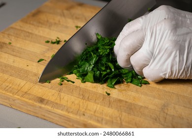 A chef chopping parsley on wooden cutting board. - Powered by Shutterstock