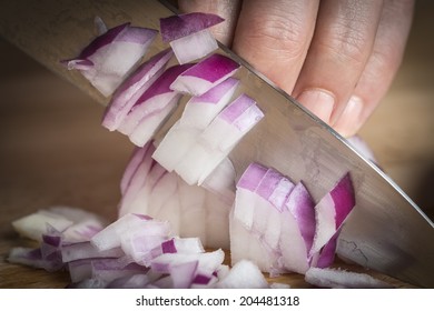 Chef chopping a red onion with a knife on the cutting board - Powered by Shutterstock