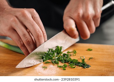 Chef chopping spring onion on wooden cutting board - Powered by Shutterstock