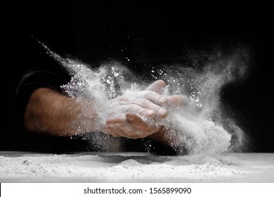 Chef clap white flour dust man hand on black background.