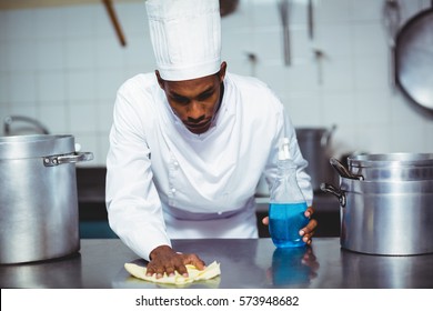 Chef Cleaning Kitchen Counter With A Bottle Of Solution And A Rag