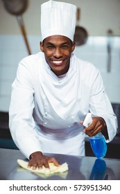 Chef Cleaning Kitchen Counter With A Bottle Of Solution And A Rag