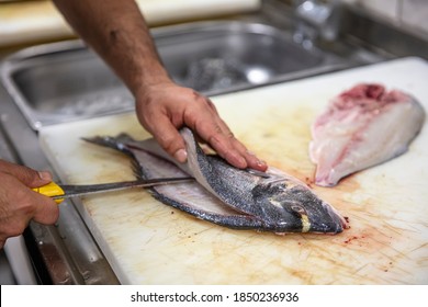 Chef cleaning sea bream in the kitchen. A Chef in a cuts up fish. Still life on the kitchen Board. Hearty food for cold regions.