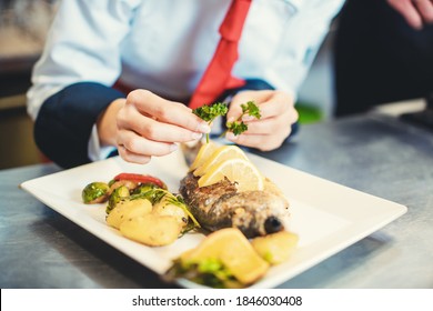 Chef Cook In A Fancy Restaurant Kitchen Finishing A Dish With Care And Diligence