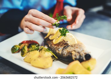 Chef Cook In A Fancy Restaurant Kitchen Finishing A Dish With Care