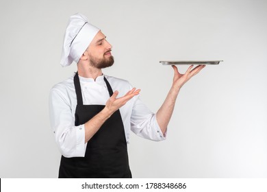 Chef cook holding an empty plate. Portrait of chef cook showing tray. Restaurant chef is demonstrating something. Concept - demonstration of dishes in restaurant. Restaurant menu. Guy in clothes cook - Powered by Shutterstock