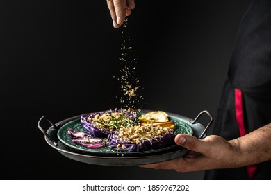 Chef Cook Preparing Vegetables Autumn Dish Of Red Cabbage Baked With Nuts, Quince And Apples, Flying Nuts Scattering In A Freeze Motion.