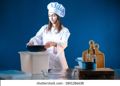 Chef Cook Woman. Woman Cook Takes A Pan Out Box. Female Cook Uncovers Kitchen Tools. Chef  Puts Dishes In A Drawer. Concept - Restaurants Are Closed. Chef Is Preparing To Move. Bankruptcy Restaurant