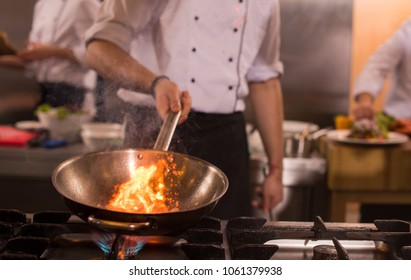 Chef cooking and doing flambe on food in restaurant kitchen - Shutterstock ID 1061379938