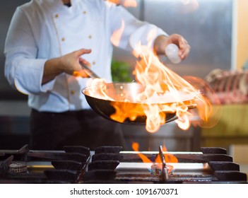 Chef Cooking And Doing Flambe On Food In Restaurant Kitchen