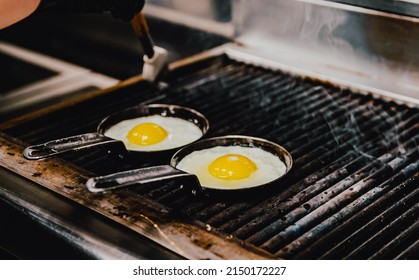 Chef Cooking Eggs In Pan On Grill In Kitchen