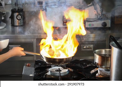 Chef Cooking With Flame In A Frying Pan On A Kitchen Stove