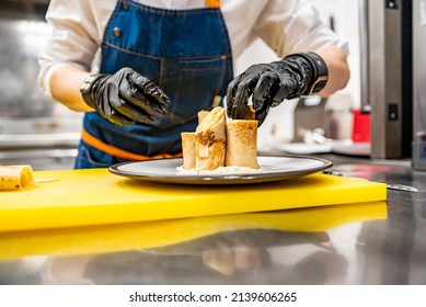 chef cooking food. Chef's hands in gloves cooking fried thin pancakes crepe stuffed potato with herring fish on kitchen