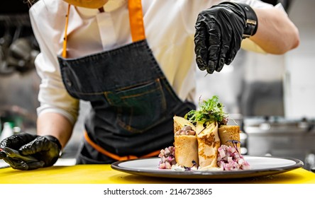 Chef Cooking Food. Chef's Hands In Gloves Cooking Fried Thin Pancakes Crepe Stuffed Potato With Herring Fish On Kitchen