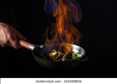 Chef Cooking Food In Pan With Fire Flame On Black Background. Restaurant And Hotel Service Concept.