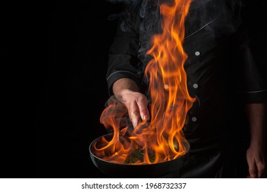 Chef Cooking Food In Pan With Fire Flame On Black Background. Restaurant And Hotel Service Concept. Free Advertising Space