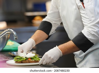 Chef cooking food in restaurant kitchen, close-up. Cook hands preparing breakfast