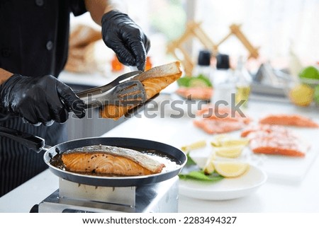 chef cooking salmon steaks in the kitchen