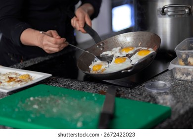 Chef cooking several eggs simultaneously in large pan during breakfast preparation
