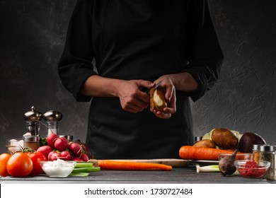 The chef cooks a dish of potatoes and vegetables. Peels the potatoes on the background with the ingredients. Diet, vegetation, proper and tasty food. Sale of vegetables, market, organic vegetables. - Powered by Shutterstock